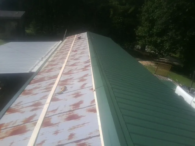 Old rusted panels beside newly installed green metal roofing — Wind Damage Roof Repair by Roofing Brothers in Maryville